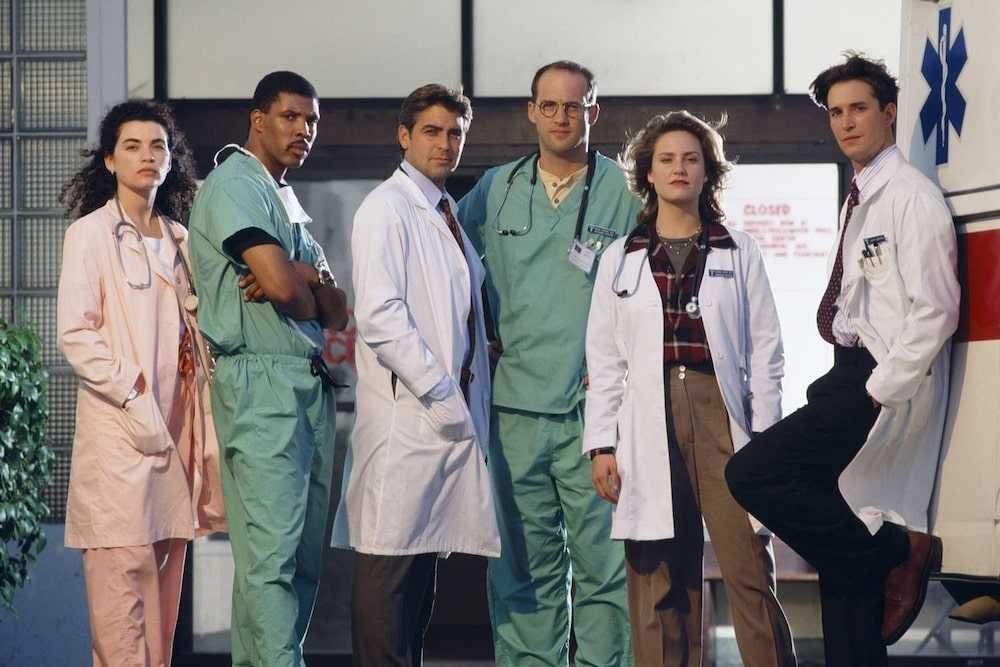 A promotional still from season 1 of "ER," with the entire cast standing outside in power poses as their hair blows in the wind